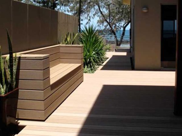 Low maintenance composite deck featuring built-in beach seat and raised garden beds. Low Maintenance Composite Deck with Custom Bench Seating